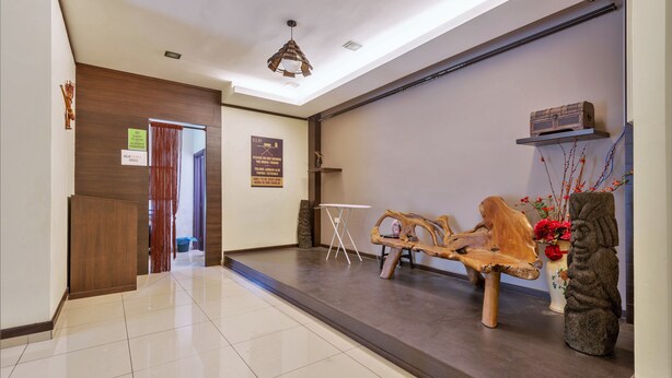 A hotel lobby with a wooden reception desk, a white folding table, and a ceiling light fixture. - Kesang Laut Hotel (Muar)