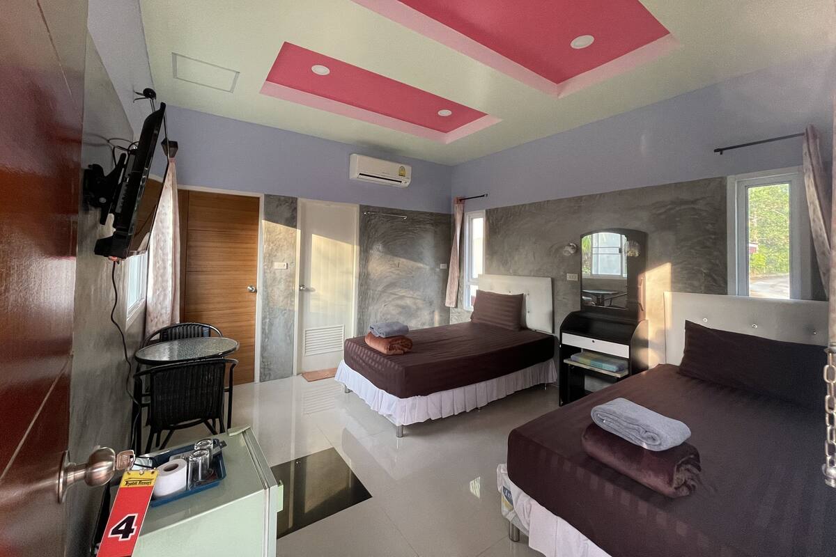 A hotel room with a bed, a desk, a chair, a mirror, and a window.