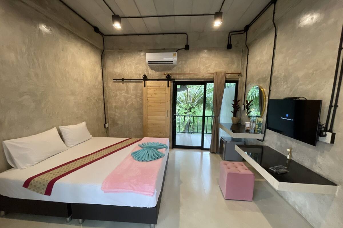 A bedroom with a bed, a TV, a bathroom with a bathtub, and a sliding door leading to a balcony.