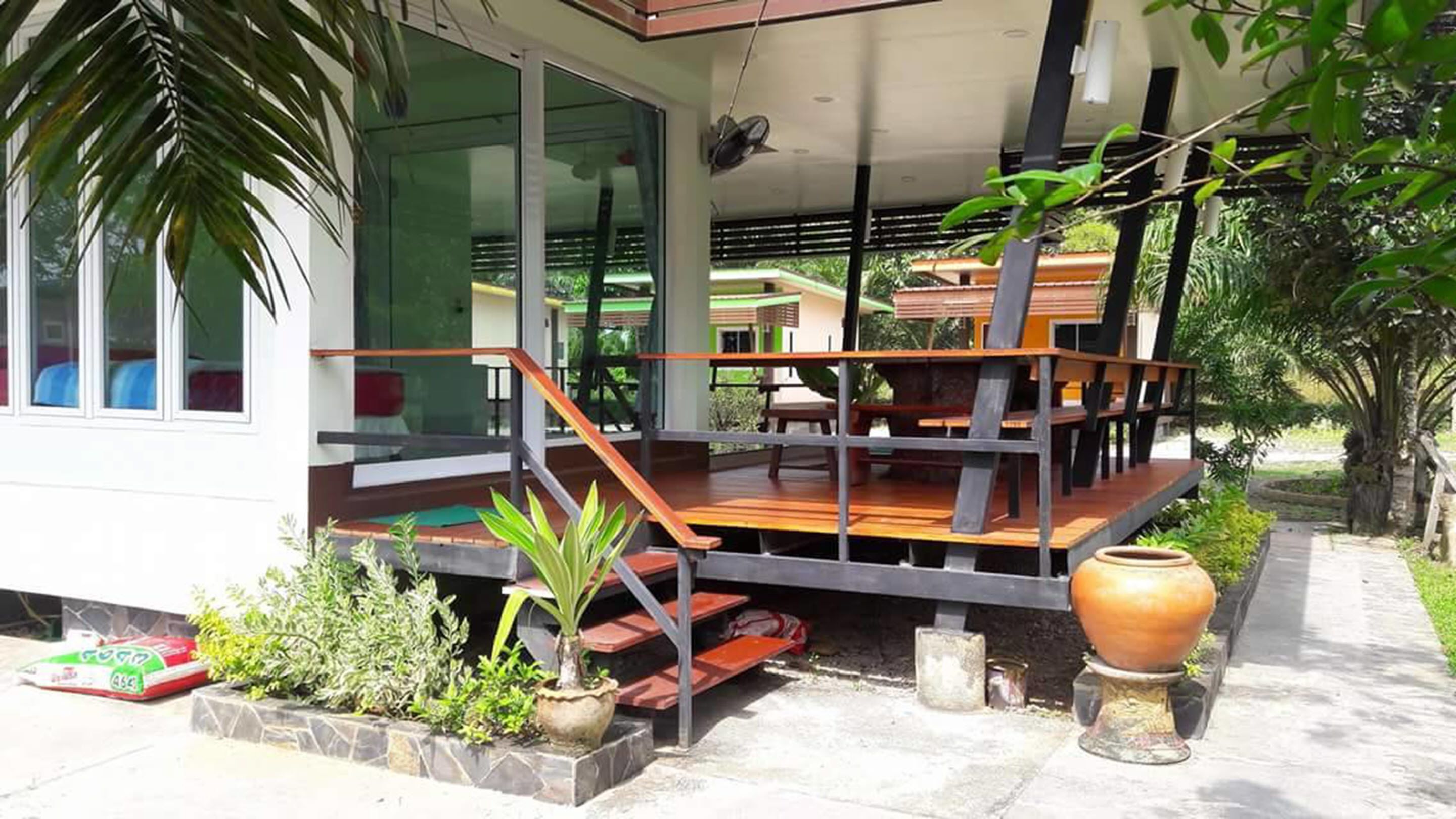 Una casa moderna con terraza de madera, puertas de cristal y un ventanal grande.
