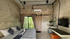 Een slaapkamer met een bed, een televisie, een klein bureau en een raam met gordijnen.