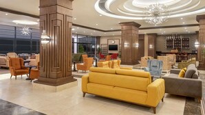 A spacious lobby with a yellow sofa, multiple armchairs, and a bar area with shelves. - Ramada Resort by Wyndham Unye (Ünye)