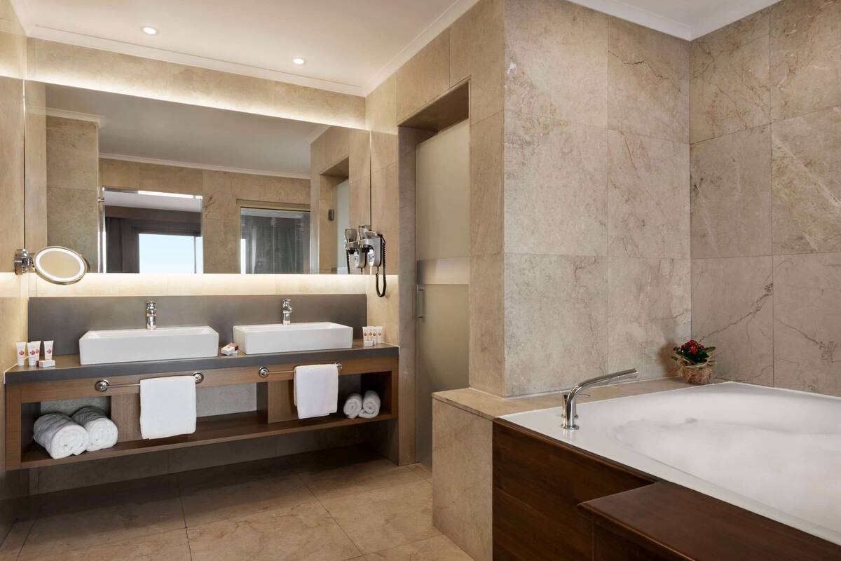 Un baño moderno con dos lavamanos, un espejo grande y una bañera.