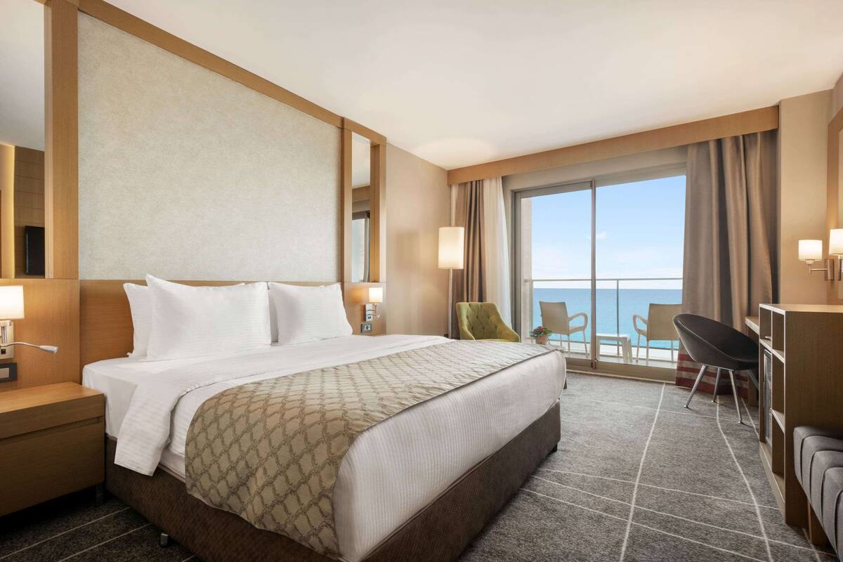 Habitación de hotel con una cama grande, un escritorio, una silla y vista al océano.