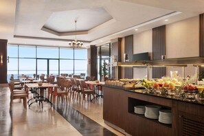A modern dining area with a long counter, multiple tables, and chairs. - Ramada Resort by Wyndham Unye (Ünye)