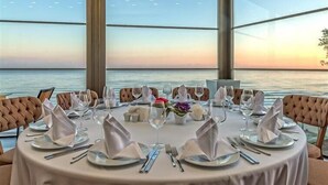 A round dining table set for six with white tablecloth, silverware, and glassware, overlooking a body of water. - Ramada Resort by Wyndham Unye (Ünye)