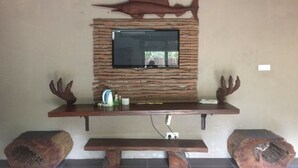 A stone wall with a flat-screen TV mounted above a wooden entertainment unit.