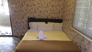 A neatly made bed with a brown bedspread and white pillows, a rolled white towel, and a headboard.