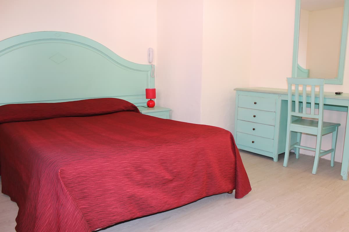 A bedroom with a bed, a nightstand, a dresser, and a mirror.
