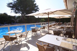 An outdoor pool area with lounge chairs and tables, surrounded by trees and a clear sky. - Hôtel Arcu Di Sole (Olmeto)