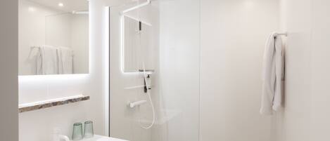 Un baño moderno con un lavabo blanco, cabina de ducha con paredes de vidrio y una toalla colgada en la pared.