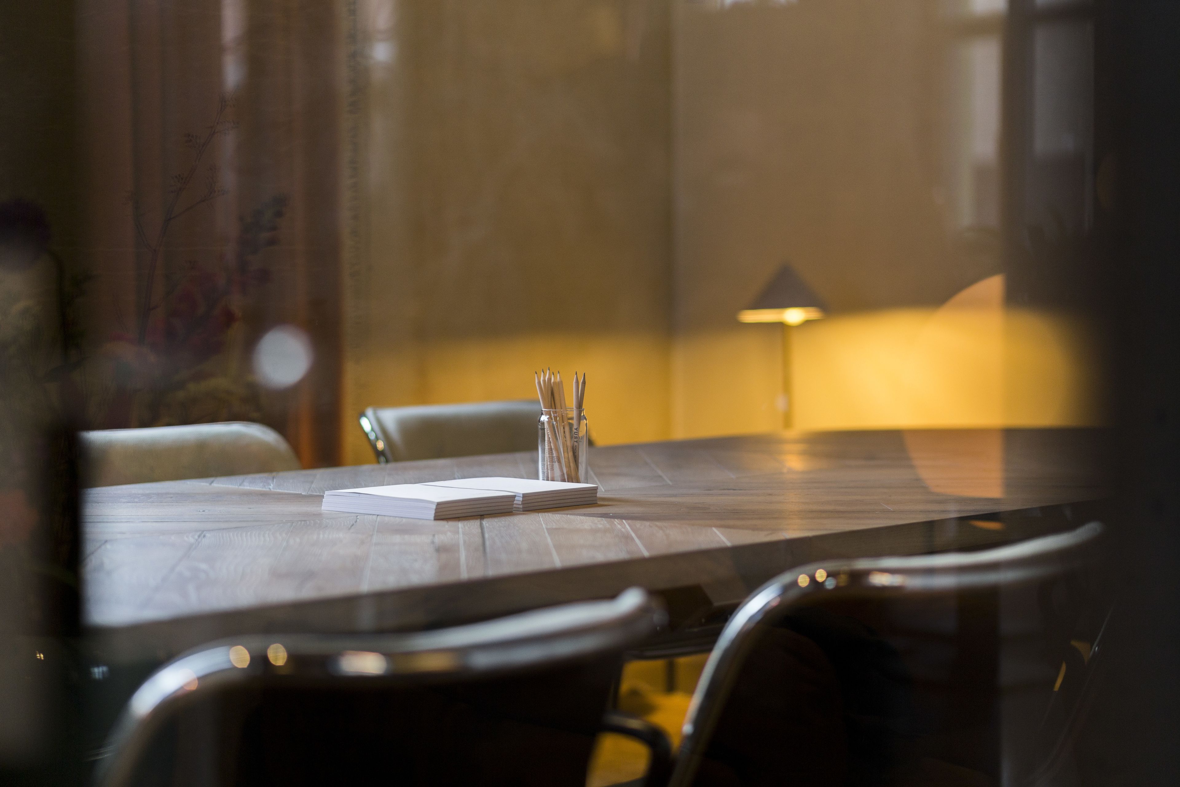 Une table de conférence avec des chaises, une lampe et un carnet.