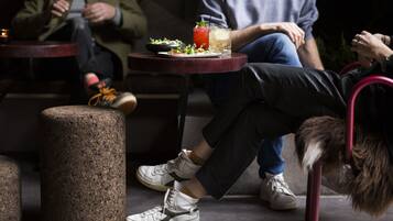 A person sitting on a chair with a table in front of them, a drink, and a plate of food.