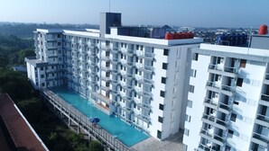 A high-rise building with multiple balconies, a rooftop pool, and a view of the surrounding area. - Indoluxe Rent Apartment Jogja (Depok)