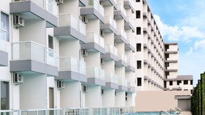 A modern hotel with a pool, multiple balconies, and a clear sky. - Indoluxe Rent Apartment Jogja (Depok)