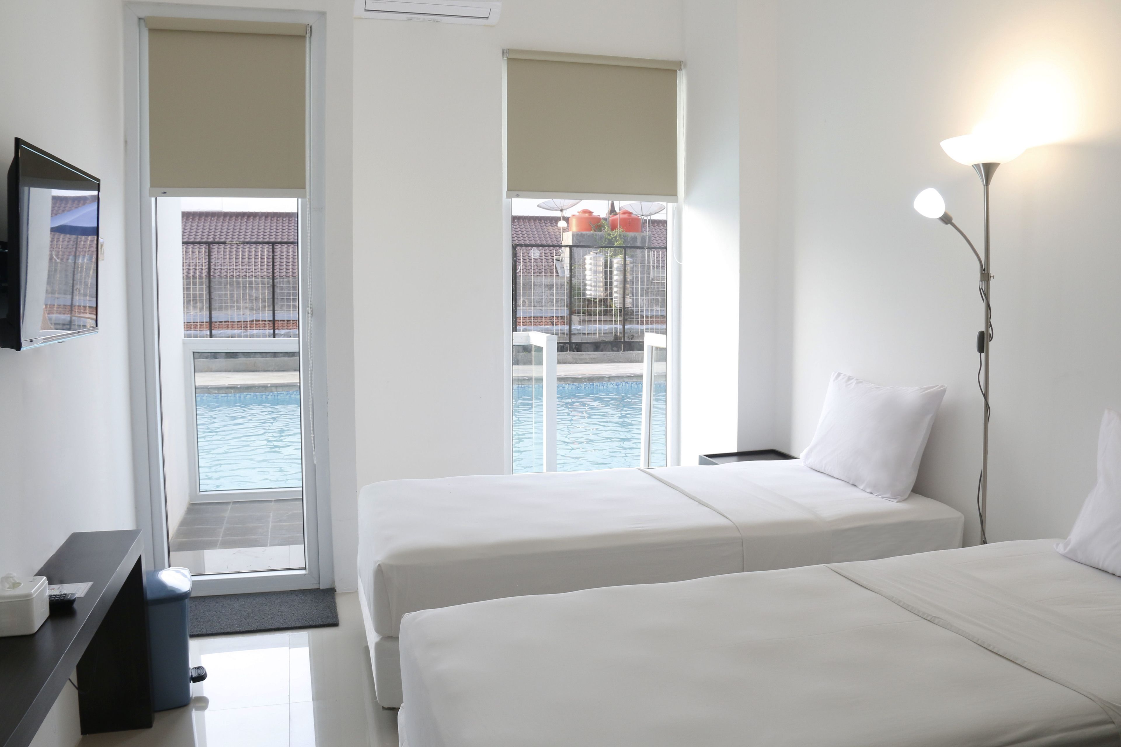 Habitación de hotel con dos camas, televisión y vista a una piscina.