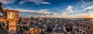 Ein weiter Panoramablick auf eine Stadtlandschaft mit einem markanten Turm und verschiedenen Gebäuden, darunter eine Mischung aus historischer und moderner Architektur.