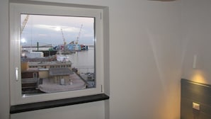 A room with a window overlooking a harbor, a ceiling light, and a wall-mounted switch. - Aquarium Rooms (Genoa)