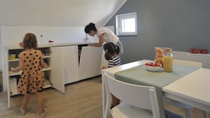 A modern kitchen with white cabinetry, a dining table with a green tablecloth, and a window providing natural light. - Aquarium Rooms (Genoa)