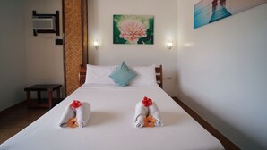 Una habitación de hotel con una cama, una mesita, aire acondicionado instalado en la pared y dos cuadros.