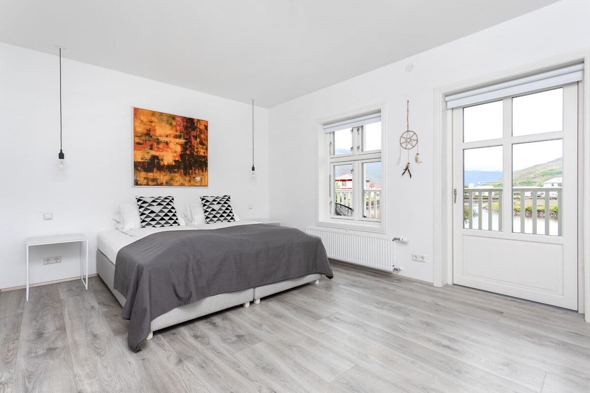 A bedroom with a bed, a window, and a view of the outside.