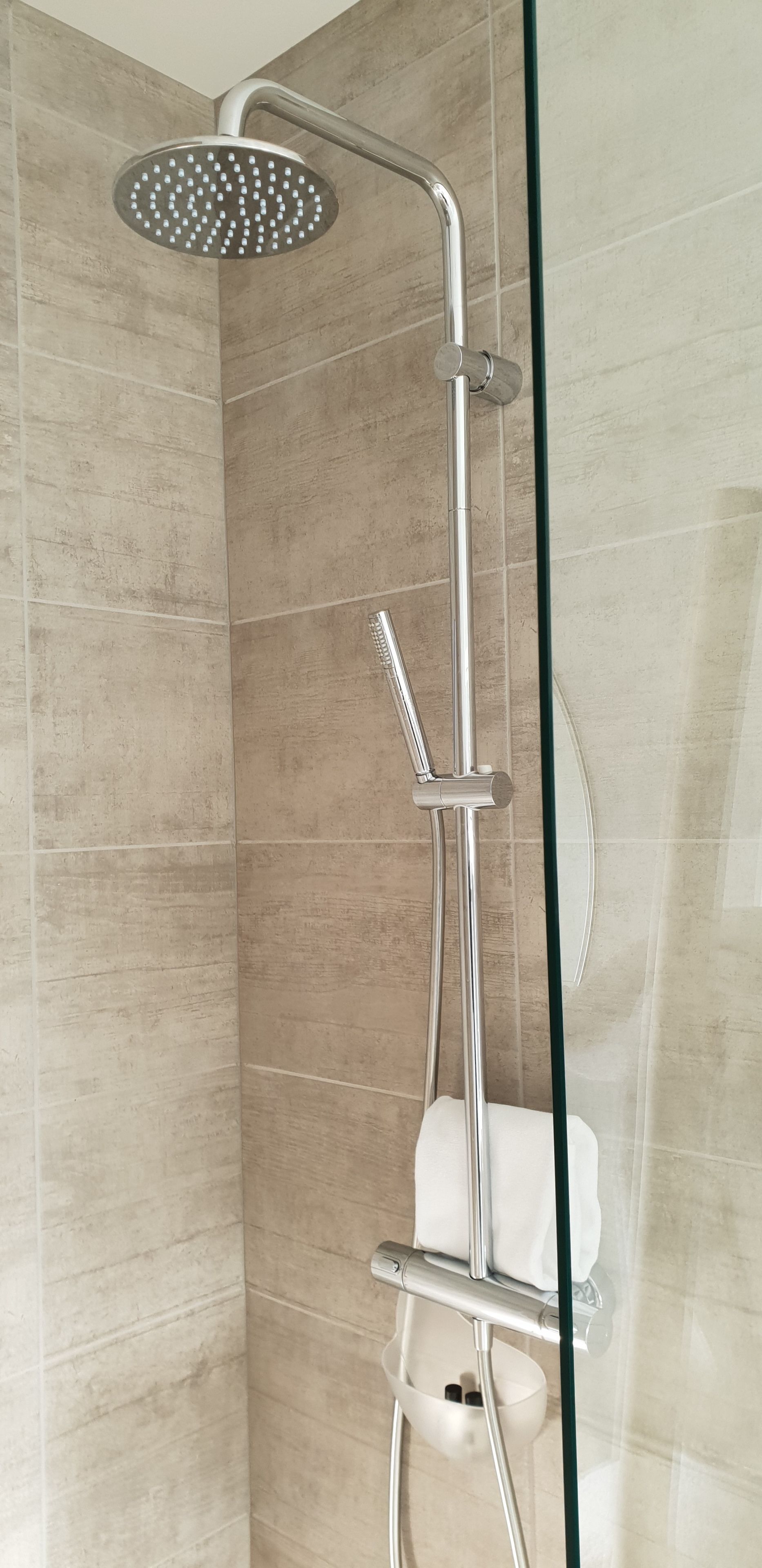 A shower with a handheld showerhead and a wall-mounted faucet.