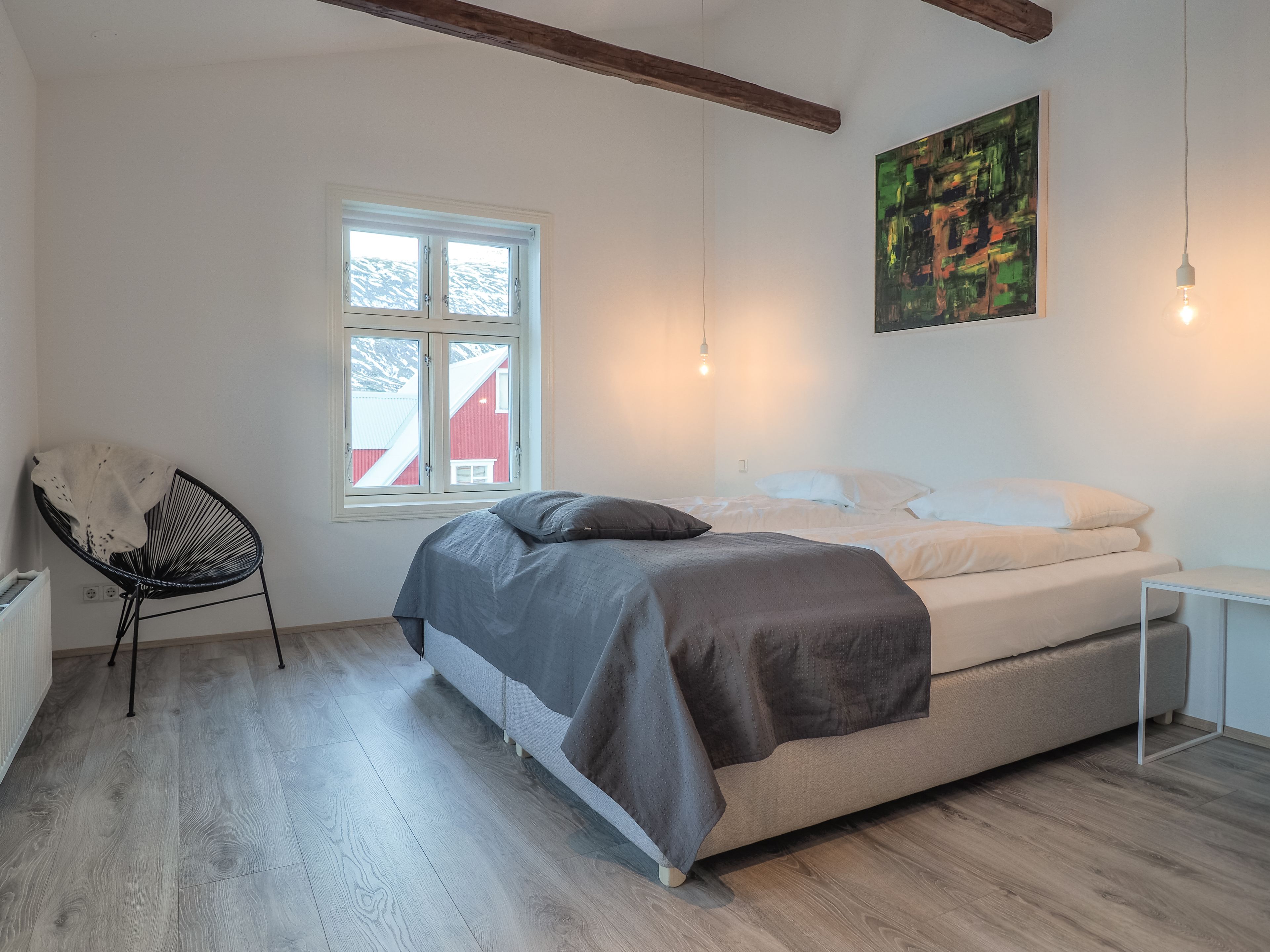 Een slaapkamer met een bed, een stoel, een raam en een schilderij.