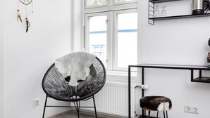 Una cocina moderna con una silla y un taburete negros, una ventana con persianas y un atrapasueños en la pared.