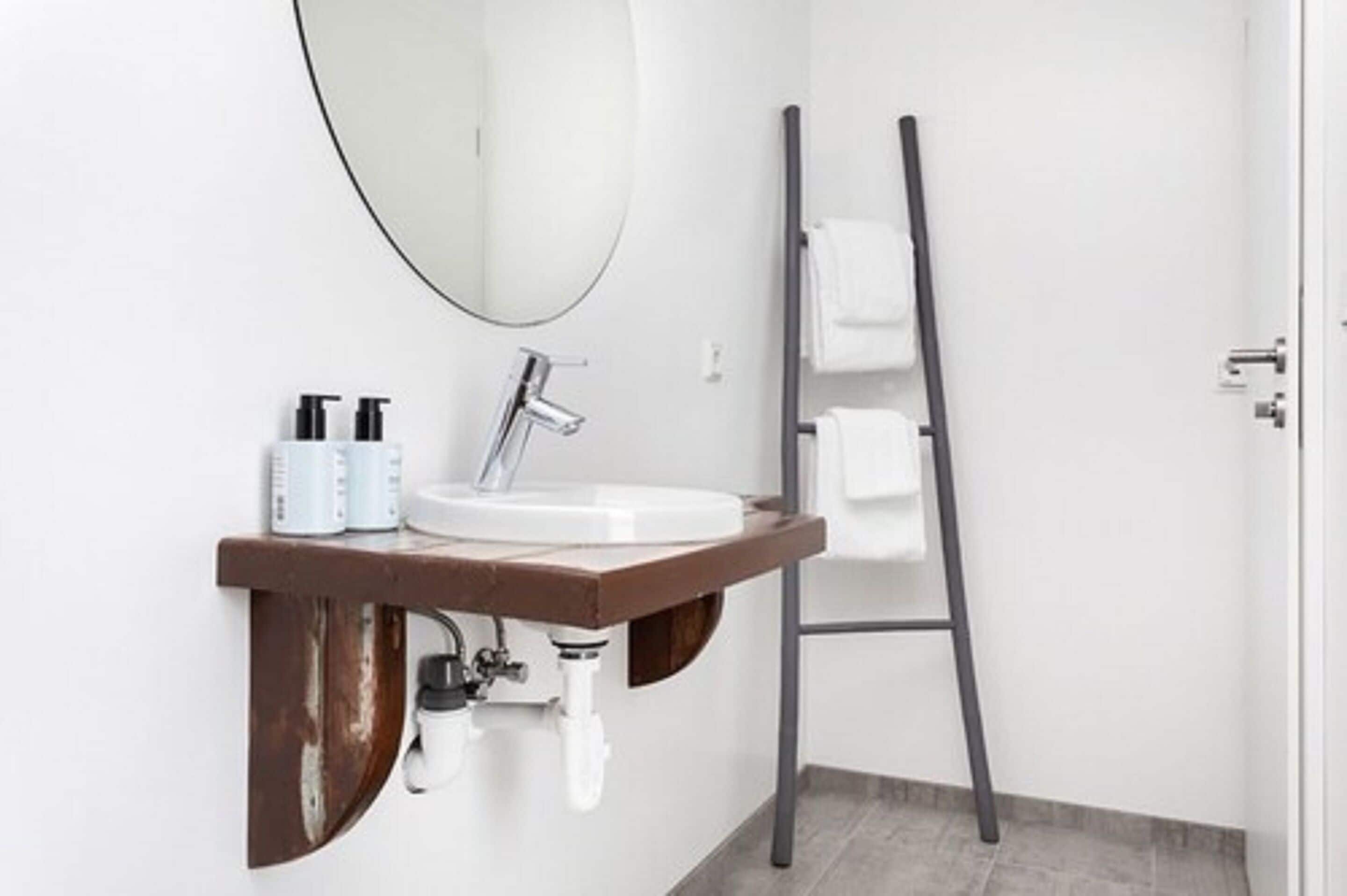 A bathroom with a white sink, a mirror, and a towel rack.