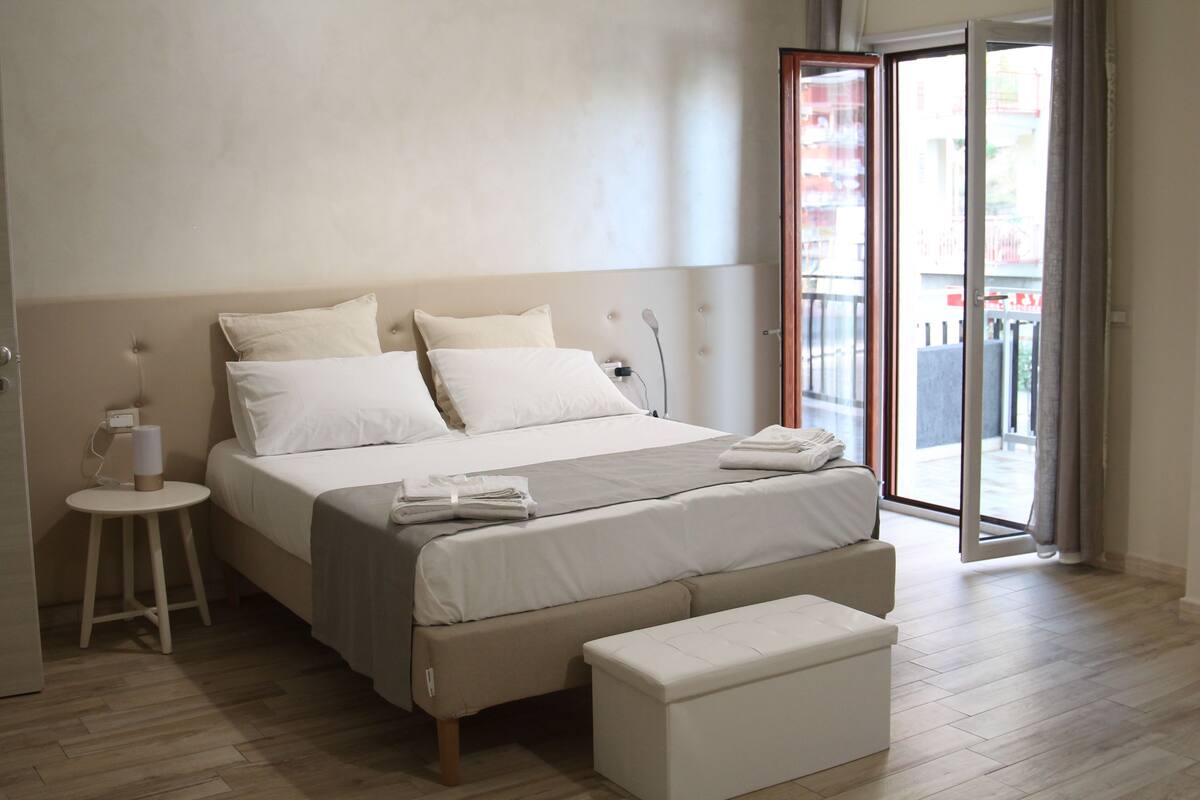 A modern bedroom with a large bed, a bedside table, and a bench.