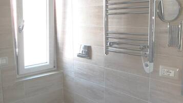 A bathroom with a toilet, bidet, and a towel rack with a mirror.