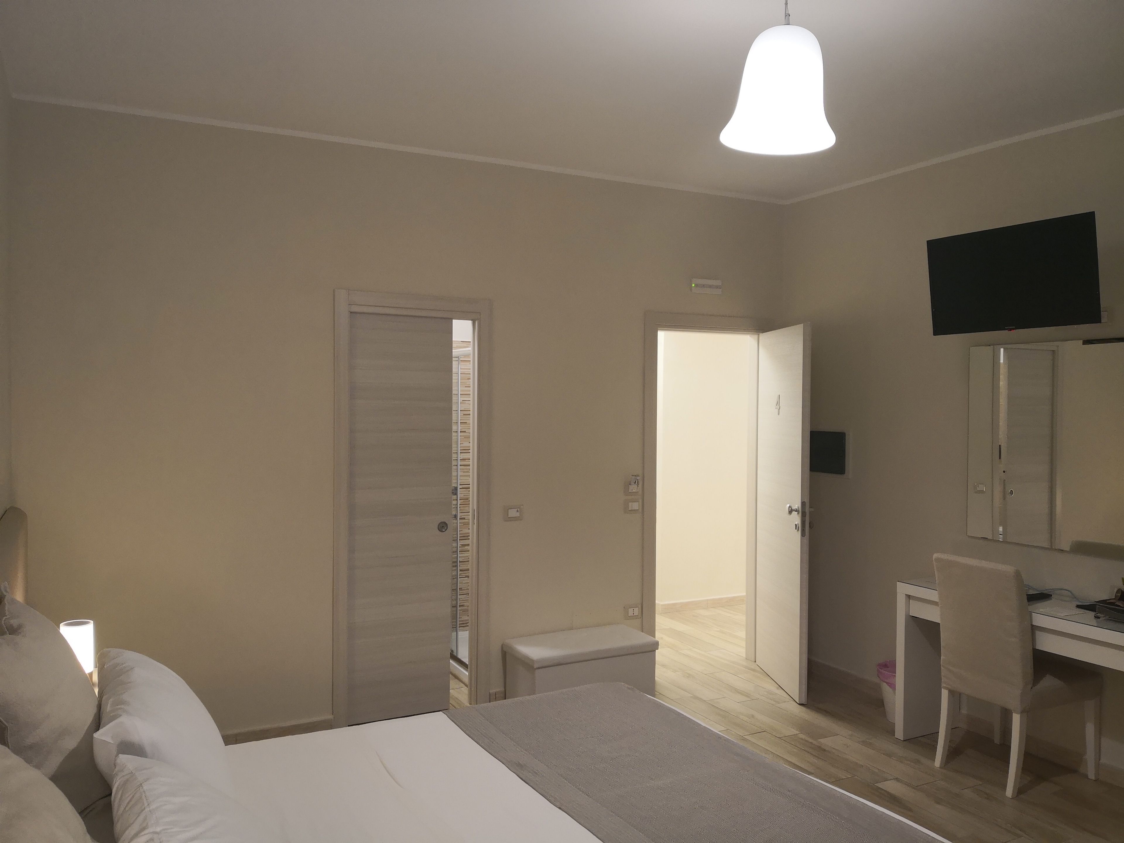 Ein Schlafzimmer mit einem Bett, einem Schreibtisch, einem Stuhl und einem Fernseher an der Wand.