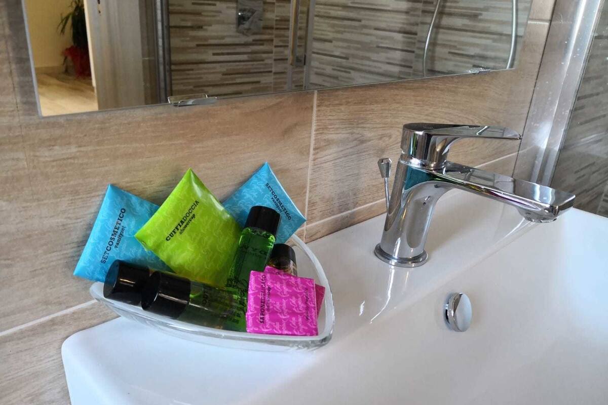 A bathroom sink with a chrome faucet, a mirror above it, and toiletries in a clear glass container.