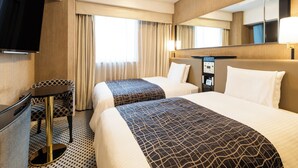 Een hotelkamer met twee bedden, een bureau, een televisie en een grote spiegel.