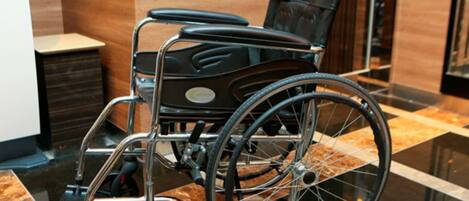 A wheelchair in a modern lobby with a marble floor and wooden paneling.