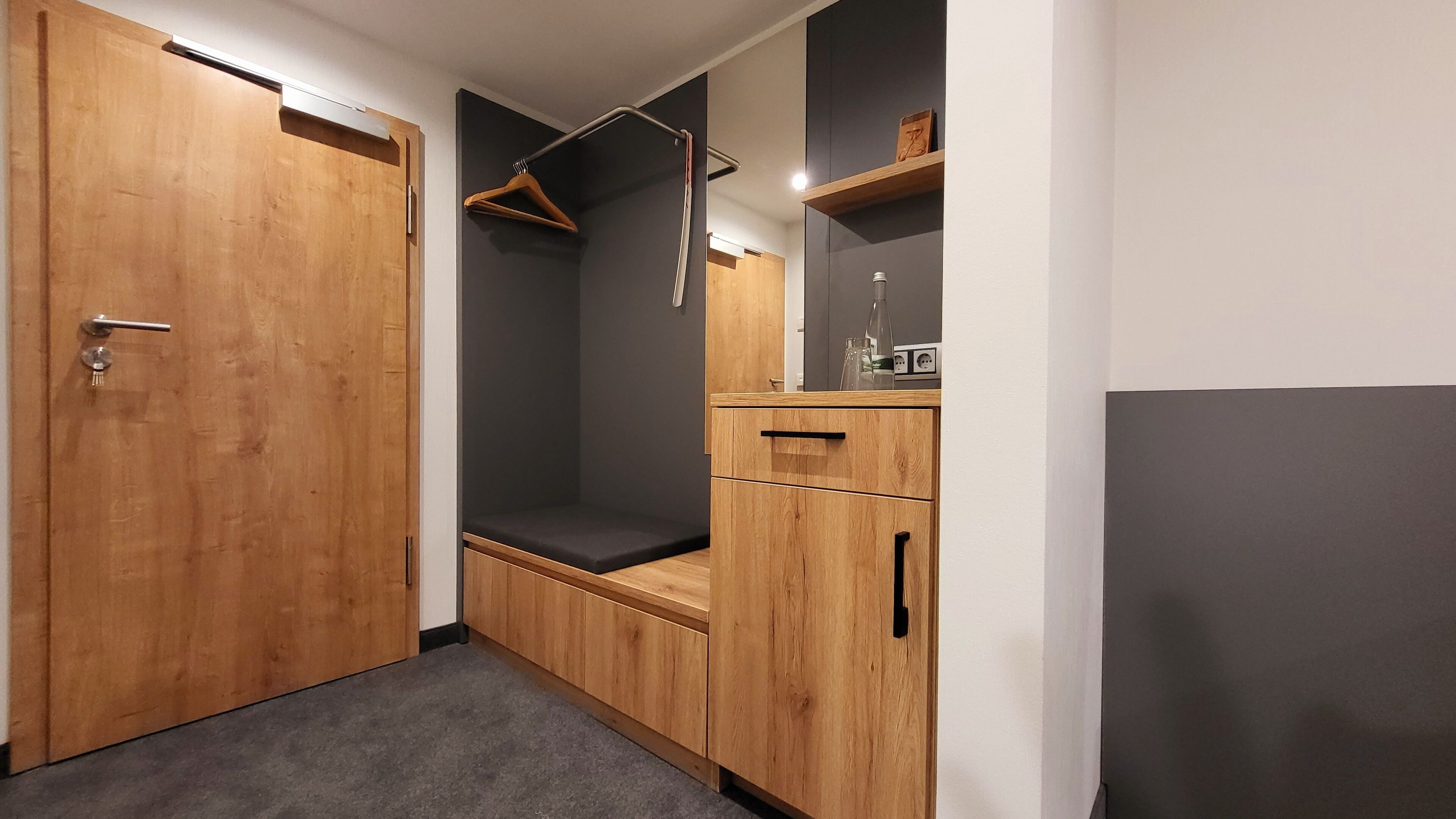A walk-in closet with wooden doors, a hanging rack, and a bench.