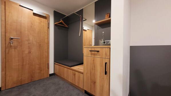 A walk-in closet with wooden doors, a hanging rack, and a bench.