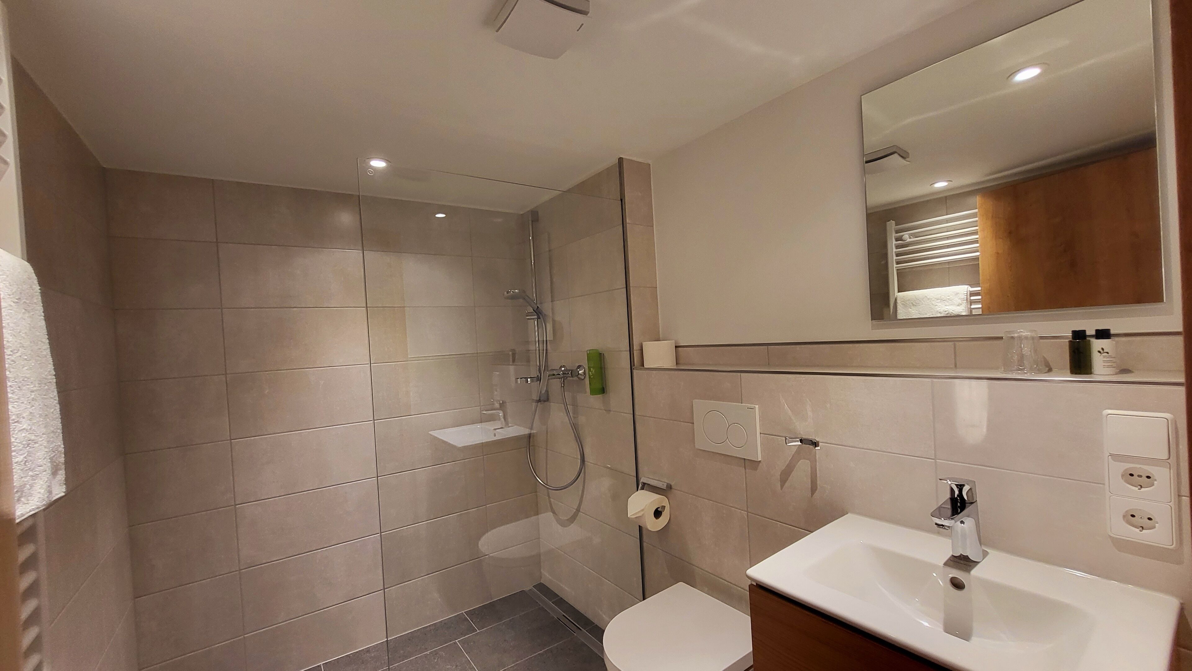 A modern bathroom with a glass-enclosed shower, a white sink, and a mirror above the sink.
