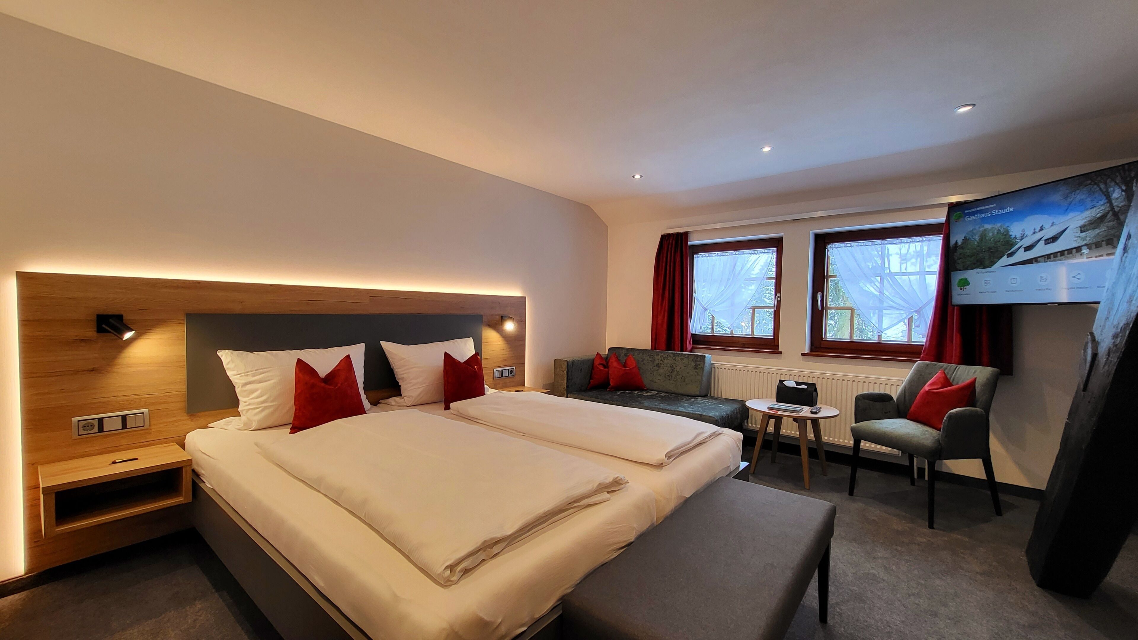 A hotel room with two beds, a sofa, a small table, and a TV.