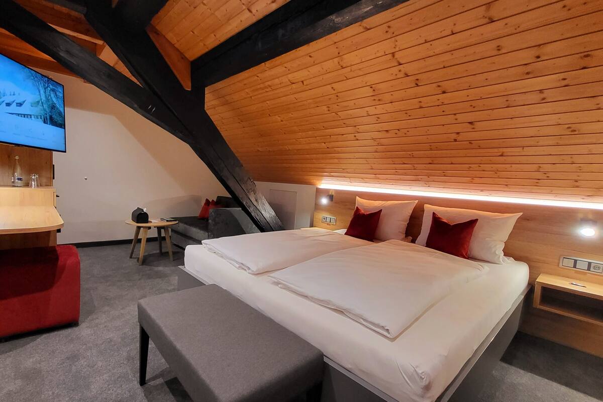 A modern bedroom with a large bed, bedside tables, a desk, and a television.