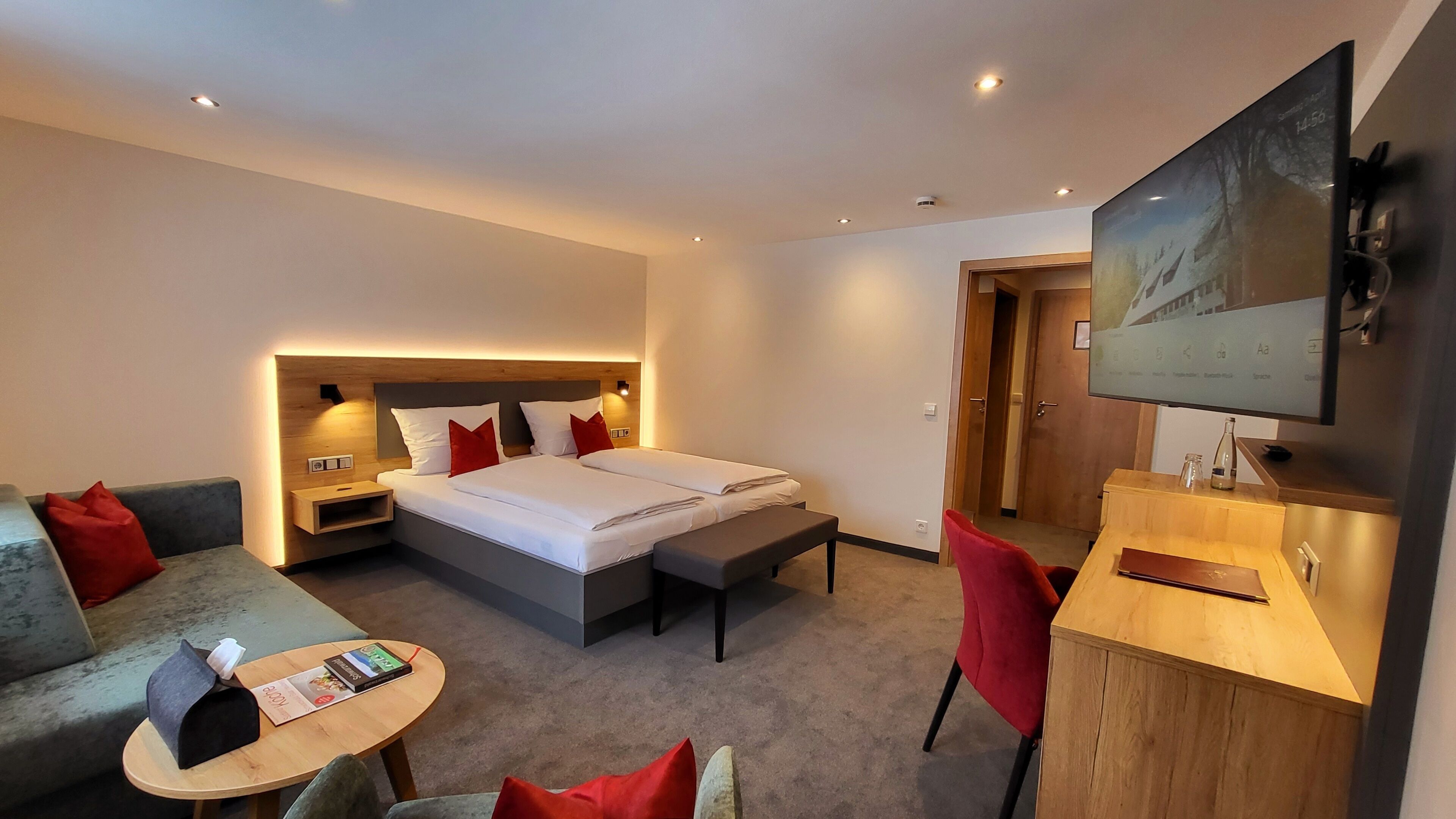 Habitación de hotel con cama, sofá, escritorio y televisión.
