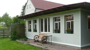 A house with a sloped roof, multiple windows, and a wooden bench outside.
