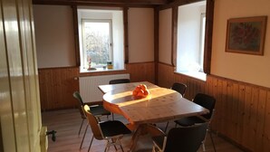 A dining area with a wooden table and chairs, a window with a view, and a radiator.