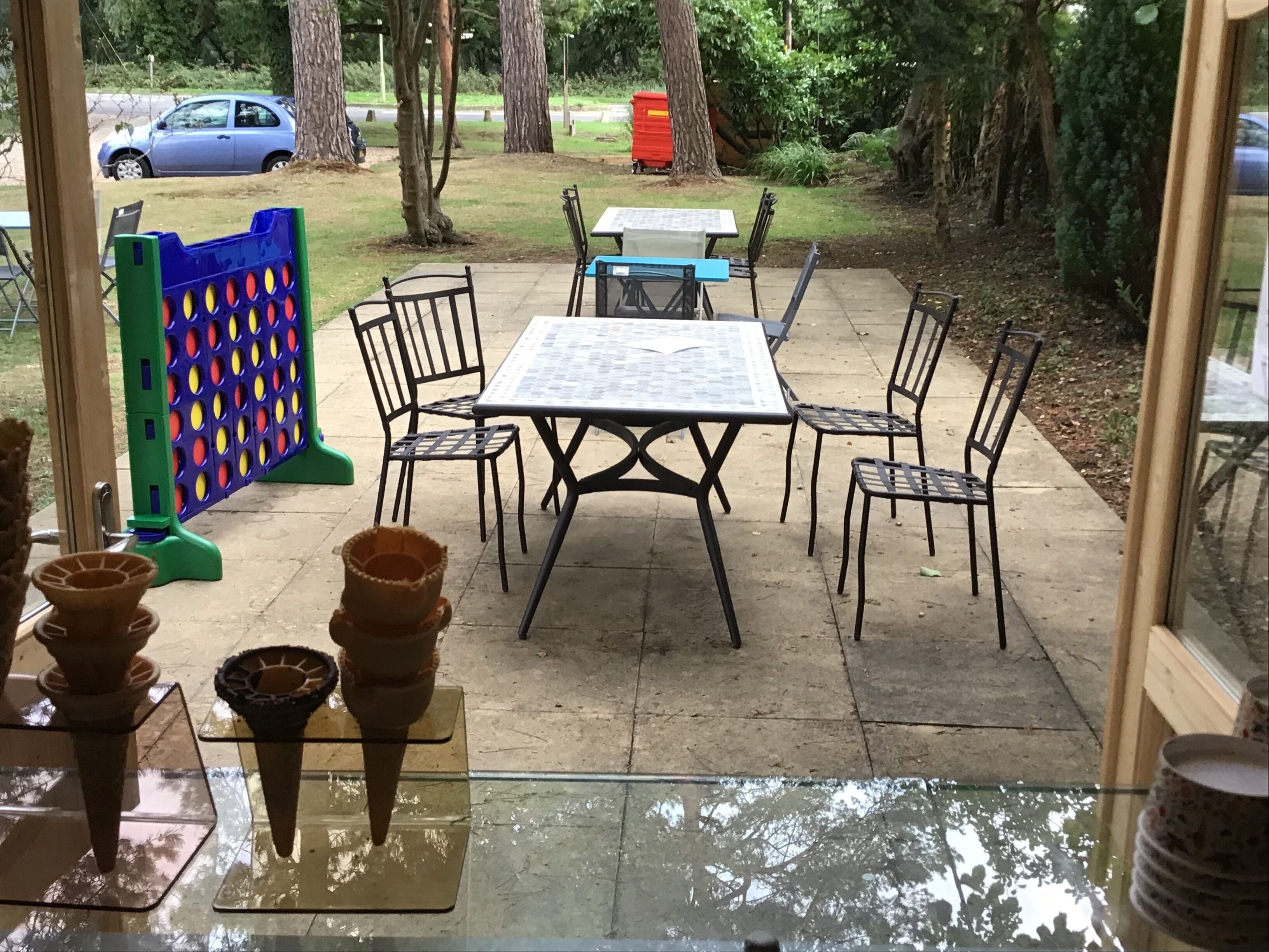 An outdoor patio with a table and chairs, a children's play area, and a car in the background.