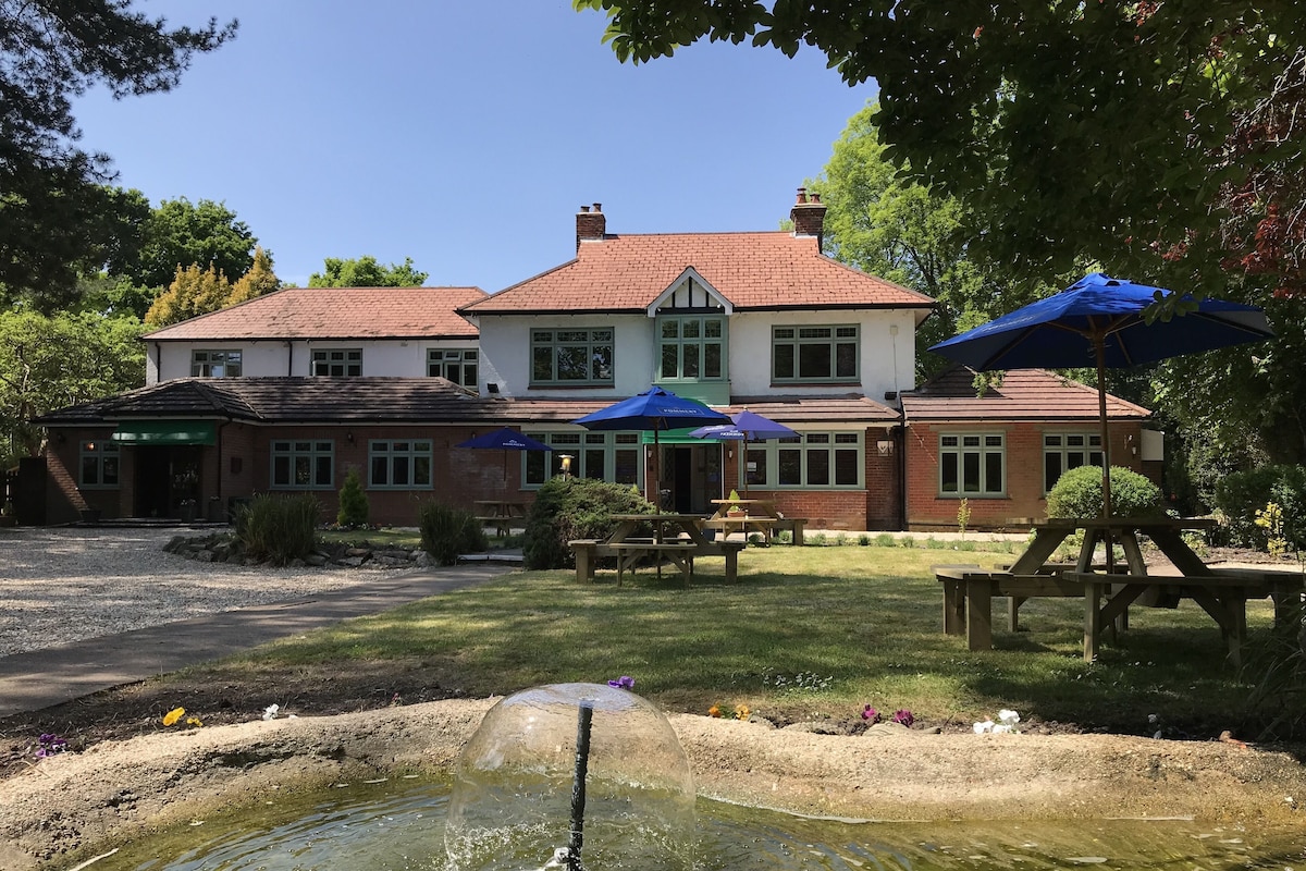 A large house with a pond, outdoor seating, and a well-maintained garden.