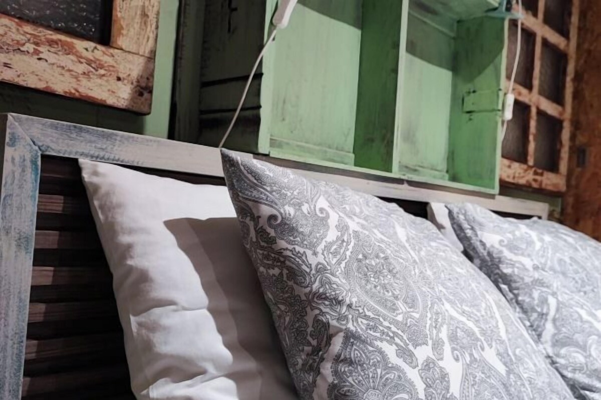 A bed with a white and gray patterned pillow and a plain white pillow.