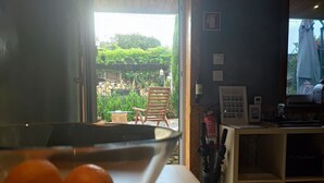 Una habitación con una mesa, una silla, un extintor y vistas al jardín exterior.
