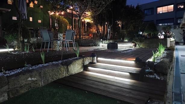 Un área de patio al aire libre con cubierta de madera, muros de piedra y un conjunto de asientos.