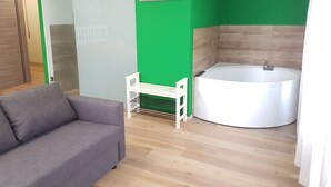 Un baño moderno con bañera, pared verde y un estante blanco pequeño.