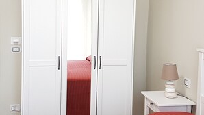 Un armario blanco con dos puertas y un espejo.